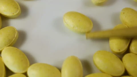 Lemon oval pressed vitamins, one tablet is pushed and it rotates around its axis Stock Footage 144855312