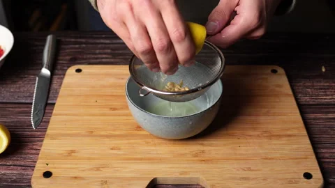Lemon pressed over sieve catching pulp and seeds Stock Footage 301446316
