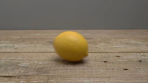 Lemon rolling on a wooden surface on a gray background. 스톡 동영상 268983612