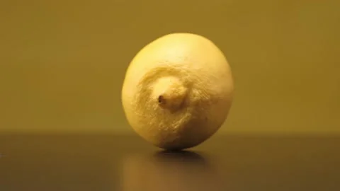 A lemon rolls on a black table on a yellow background. Close up. Stock Footage 144334335