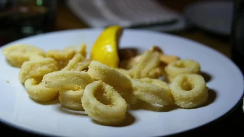 Lemon seafood fork squid rings Hand uses fork to pick up calamari ring from Stock Footage 320644057