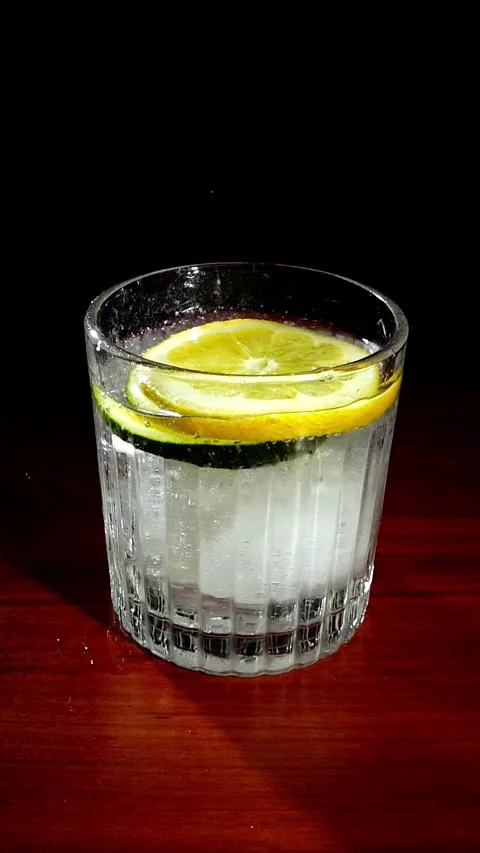 Lemon Slice Dropping into Cucumber Gin Tonic Cocktail Slow Motion Stock Footage 324599976