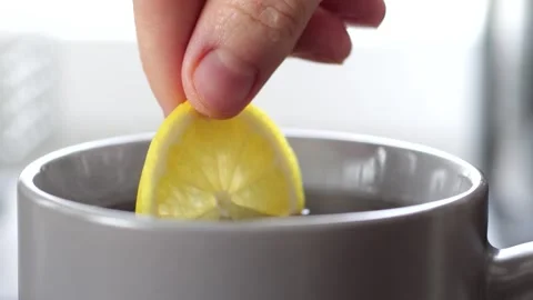 Lemon slice dropping into steaming tea in slow motion Stock Footage 305878452