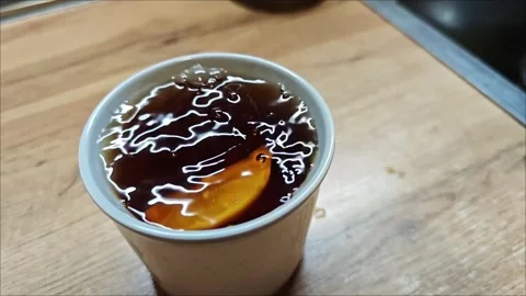 Lemon slice falling and floating in a tea cup Vidéo 307494357