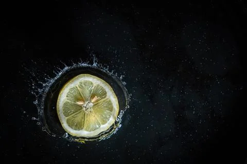 Lemon slice falling into the water with black background. Stock-Fotos