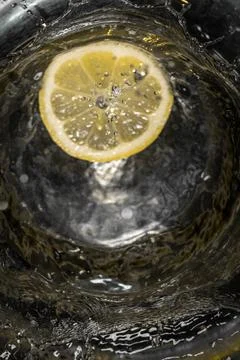 Lemon slice falling into the water with black background. Stock Photos