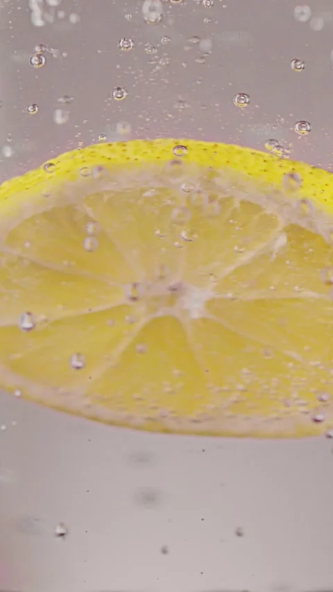 Lemon slice falls into sparkling water Vídeo Stock 237702268
