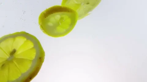 Lemon slice fruit splash falling down into white alcohol cocktail and water Stock Footage 76251928