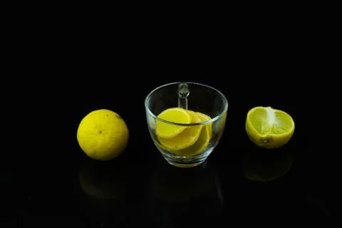 Lemon slice pieces arranged in tea glass closeup black background Stock Photos