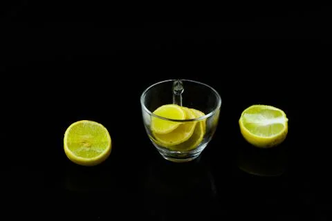 Lemon slice pieces arranged in tea glass closeup black background Stock Photos