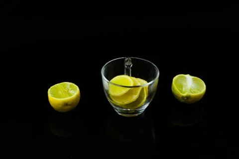 Lemon slice pieces arranged in tea glass closeup black background Stock Photos