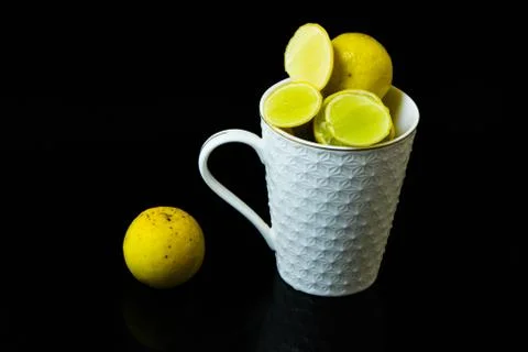 Lemon slice pieces arranged in tea glass closeup black background Stock Photos