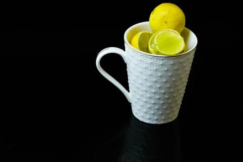Lemon slice pieces arranged in tea glass closeup black background Stock Photos
