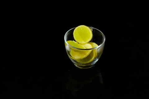 Lemon slice pieces arranged in tea glass closeup black background Stock Photos