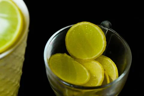 Lemon slice pieces arranged in tea glass closeup black background Stock Photos