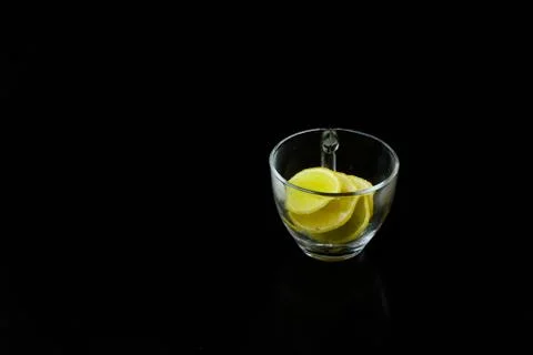 Lemon slice pieces arranged in tea glass closeup black background Stock Photos