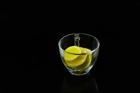 Lemon slice pieces arranged in tea glass closeup black background Stock-Fotos