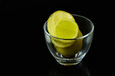 Lemon slice pieces arranged in tea glass closeup black background Stock Photos