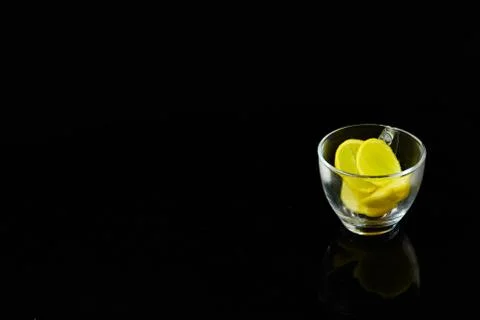 Lemon slice pieces arranged in tea glass closeup black background Stock Photos