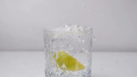 Lemon slice splashing in cold water - cool refreshing summer drinks Stock Footage 153070633