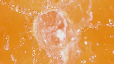 Lemon slice splashing into vibrant orange liquid slow motion Stock Footage 327573364