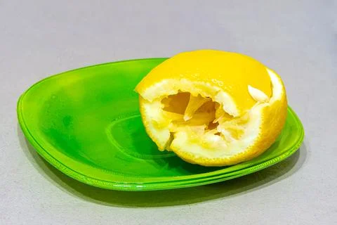 Lemon sliced and squeezed to obtain lemon juice lies on a green plate Stock Photos