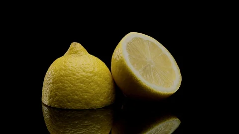 A lemon sliced in half, rotating on a black background 動画素材 128720427