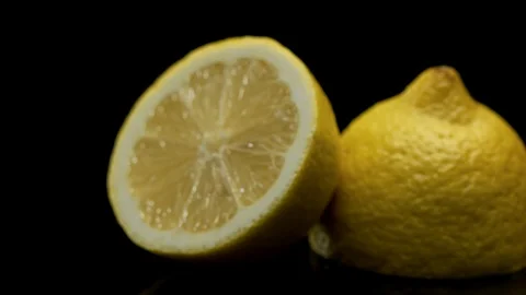 A lemon sliced in half, rotating on a black background 動画素材 128721003