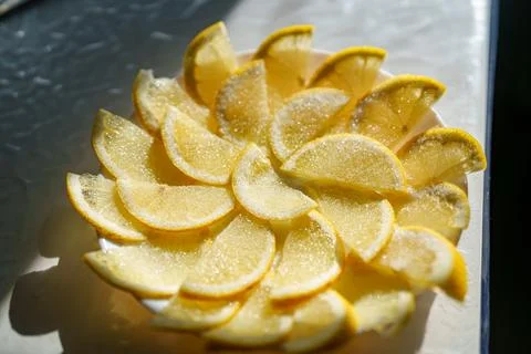 Lemon slices arranged in a circular pattern on a plate under bright sunligh.. Foto stock