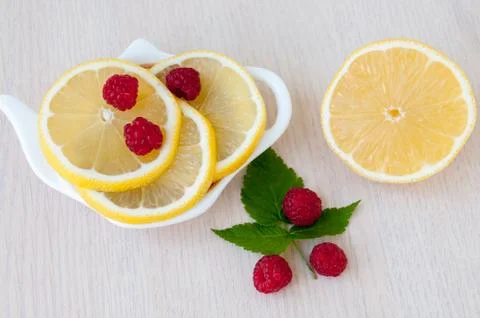 Lemon slices, berries and raspberry leaves on the table Stock Photos