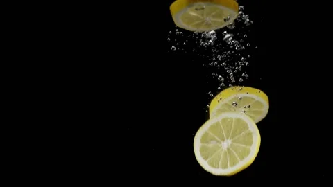 Lemon slices falling and splashing into water slow in motion on black background Stock Footage 150060059