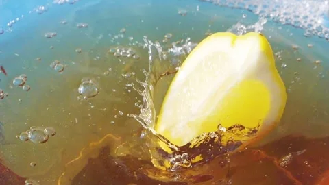 Lemon slices falling and splashing into iced tea, creating refreshing ripples Stock Footage 287695324
