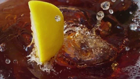 Lemon slices falling and splashing into iced tea, creating refreshing ripples Stock Footage 287695713