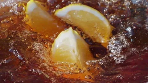 Lemon slices falling and splashing into iced tea, creating refreshing ripples Stock Footage 287696083