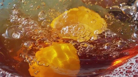 Lemon slices falling and splashing into iced tea, creating refreshing ripples Video stock 287696133