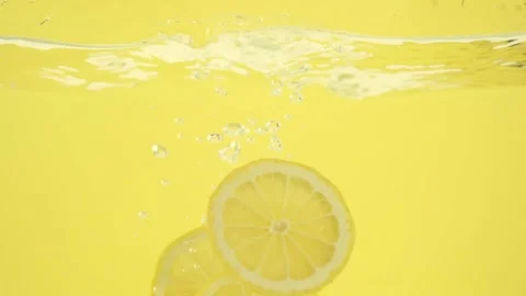 Lemon slices falling into a water isolated on yellow background, selective focus 库存影片 153479545