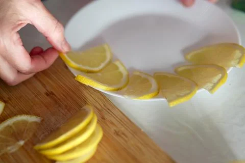 Lemon slices gracefully dance around the edge of a white plate, a citrus sy.. Stock Photos
