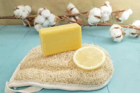 Lemon soap and lemon slice on a loofah bath scrub with cotton buds flowers,.. Foto stock
