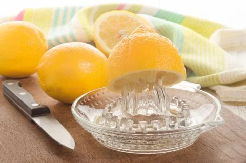 Lemon is squeezed on a lemon squeezer Stock Photos
