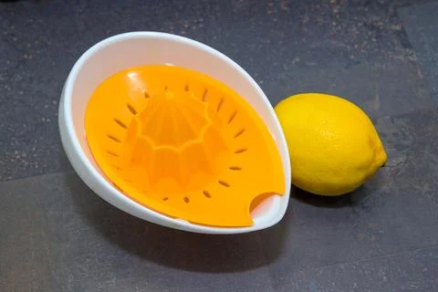 A lemon squeezer with an orange reamer and a whole lemon on a dark surface Stock Photos