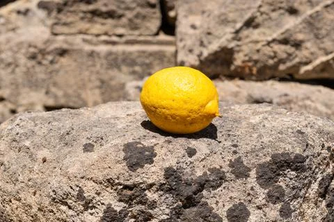 Lemon on Sunlit Stone Surface Stock Photos