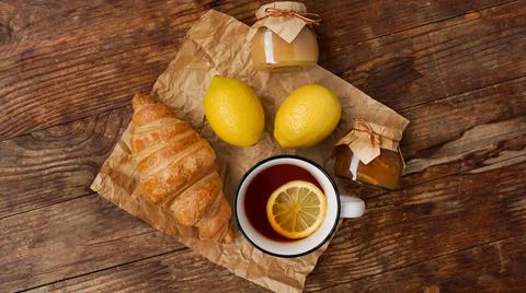 Lemon tea, home made jam, croissant on wooden table. Breakfast concept. Stock Photos