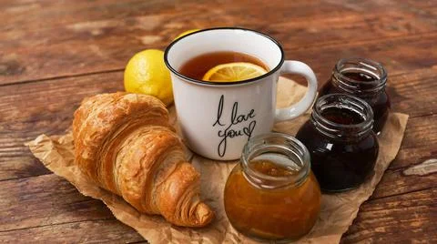 Lemon tea, home made jam, croissant on wooden table. Breakfast concept. Stock Photos