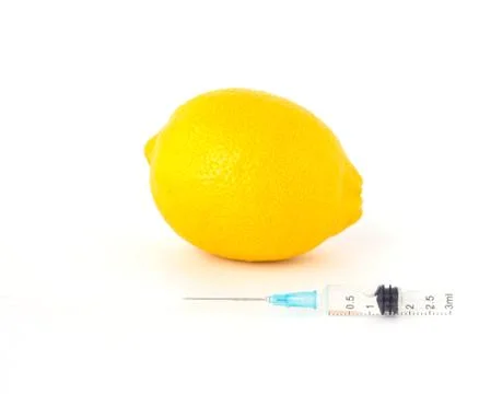 Lemon on white background next to which is a syringe with gmo and nitrates Stockfoto's