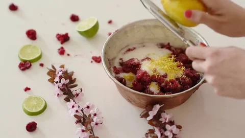 Lemon zest being grated by young girl over a pot full of raspberries and .. Video stock 73743552