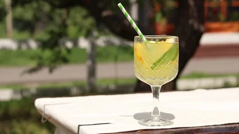 Lemonade in a glass goblet on a blurred background of nature Stock Footage 310466342