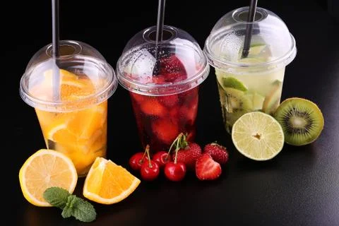 Lemonade to go. Three cups with mint, cherry, strawberry, kiwi, lime, orage, Foto stock