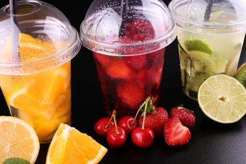 Lemonade to go. Three cups with mint, cherry, strawberry, kiwi, lime, orage, Stock Photos