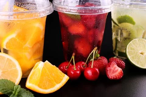 Lemonade to go. Three cups with mint, cherry, strawberry, kiwi, lime, orage, Foto stock