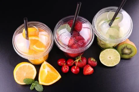 Lemonade to go. Three cups with mint, cherry, strawberry, kiwi, lime, orage, Stock Photos
